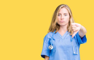 Mutsuz ve kızgın ret gösterilen ve başparmak aşağı hareketi ile negatif seyir izole arka plan üzerinde tıbbi üniforma giyen güzel genç doktor kadın. Kötü ifade.
