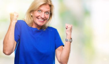 Gülümseyen ve başarı için çığlık orta yaş sarışın kadın izole arka plan çok mutlu ve heyecanlı kaldırdı, silah ile kazanan jest yapıyor. Kutlama kavramı.