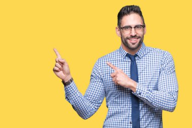 Gülümseyen ve iki elleri ve parmakları ile tarafına işaret kamera bakarak izole arka plan üzerinde gözlük takan genç iş adamı.