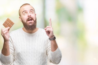 Genç hipster adam yeme çikolata üzerinde arka plan ile bir fikir ya da gülen yüz, bir numara ile parmak işaret soru sürpriz izole