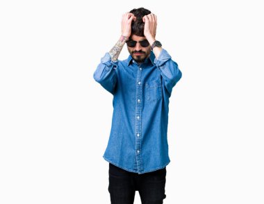 Yakışıklı delikanlı çünkü umutsuz ve stresli baş ağrısı acı izole arka plan üzerinde güneş gözlüğü takıyor ağrı ve migren. Ellerini kafasına.