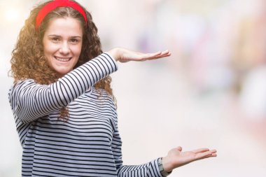 Güzel esmer kıvırcık saçlı Genç kız giyiyor kazak ile büyük ve büyük boy işaret, ölçü birimi sembol gösteren el eller izole arka plan üzerinde çizgili. Kameraya bakarak gülümsüyordu. Ölçüm kavramı.