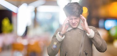 Genç yakışıklı adam giyen kış ceket baş baş ağrısı için el ile izole arka plan üzerinde çünkü stres. Migren muzdarip.