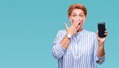 Atrractive üst düzey beyaz Kızıl saçlı kadın gösteren smartphone ekran üzerinde izole arka kapak ağız elle hata, korku, sessizlik içinde gizli kavramı korkmuş ifade için utanç ile şok