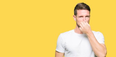 Bir şey pis ve iğrenç kokulu casual beyaz t-shirt, dayanılmaz koku, holding nefes parmak ile burun üzerinde giyen yakışıklı adam. Kötü kokuyor kavramı.