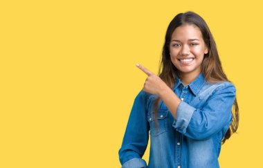 Mavi kot gömlek izole üzerinde giyen genç güzel esmer kadın yan gösteren reklam, ciddi ve sakin yüz el parmak ile işaret arka plan