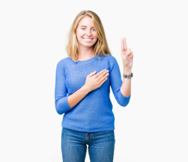 Mavi kazak izole üzerinde giyen güzel genç kadın arka plan Swearing göğüs ve parmaklar, el ile bir sadakat sözü yemin yapma