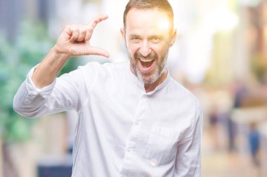 Orta yaş üzerinde gülümseyen izole arka plan ve süre seyir ve kamera boyutu işaret parmaklarıyla yapıyor el ile kendine güvenen el hareketi ağarmış komuta sizde. Ölçü kavramı.