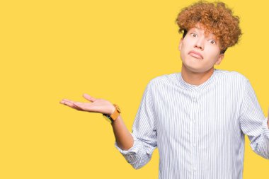 Şık gömlek clueless ve şaşkın bir ifadeyle kollar ve eller kaldırdı giyen afro saçlı genç yakışıklı iş adamı. Şüphe kavramı.