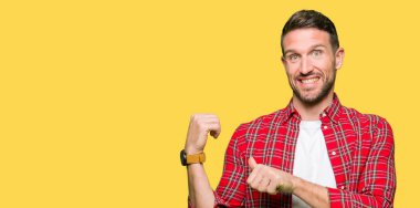 Yakışıklı adam rahat gömlek giymiş emin gülümseyen arkasından el ve kadar başparmak ile işaret