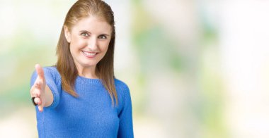 Üzerinde kış kazak giyen güzel orta yaş Olgun kadın arka plan dostu sunan karşılıklı tebrik ve davet edici gülümseyen izole. Başarılı iş.