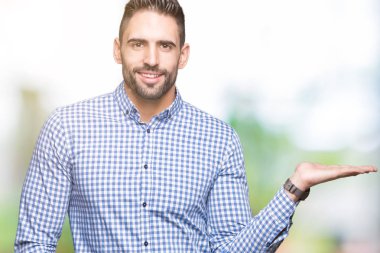 Genç yakışıklı adam neşeli sunulması ve kameraya bakarak avucunun ile işaret gülümseyen izole arka plan üzerinde.