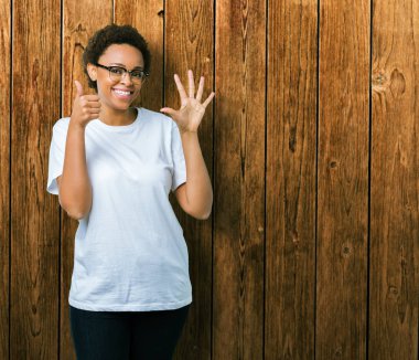 Güzel genç Afro-Amerikan kadın gözlük gösterilen ve parmakları ile işaret izole arka plan üzerinde kendinden emin ve mutlu gülümseyerek süre 6 numara.