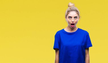 Korkuyor ve şok sürpriz ifade, korku ve heyecan yüz ile izole arka plan üzerinde mavi t-shirt giyen genç güzel sarışın ve mavi gözlü kadın.