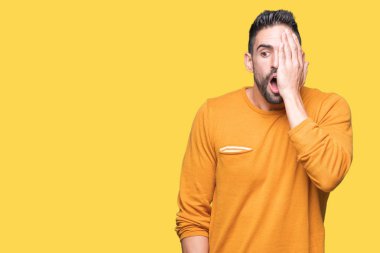 El yüz ve sürpriz duygu kendinden emin gülümseme ile tek gözüyle kapsayan izole arka plan üzerinde genç yakışıklı adam.