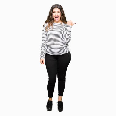 Seyir ve başparmak yanında yukarıyı mutlu yüz ile gülümseyen çizgili Süveter giyen genç güzel kadın.