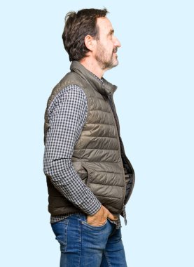 Orta yaş yakışıklı adam giyen kış yelek tarafına, seyir dinlenmek doğal yüz emin gülümseme ile pozuyla profil.