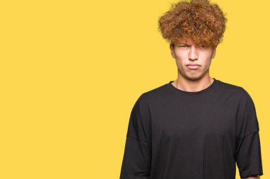 Yakışıklı genç afro saçlı siyah t-shirt şüpheci ve sinir, papatyanın üzgün sorunu nedeniyle giyiyor. Negatif kişi.