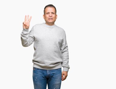 Gösterilen arka plan üzerinde spor kazak giyen orta yaş Arap adam izole ve parmakları ile işaret kendinden emin ve mutlu gülümseyerek iken üçüncü.