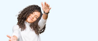 Genç güzel kadın kıvırcık saçlı sarılmak için Kollarını açarak gülümseyerek kameraya bakarak boğazlı kazak giyiyor. Neşeli ifade kucaklayan mutluluk.