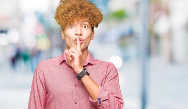 Young handsome business man with afro hair asking to be quiet with finger on lips. Silence and secret concept.
