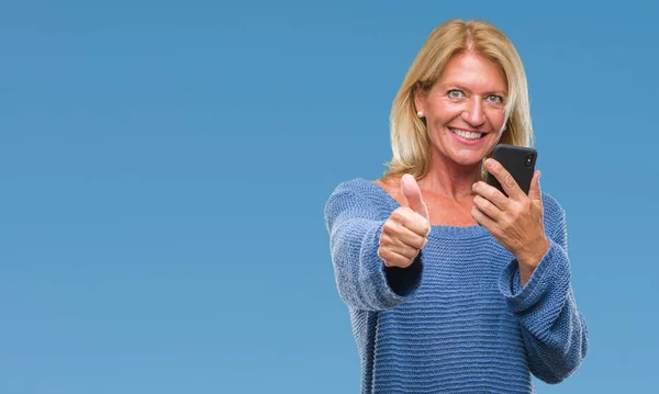 Middle age blonde woman sending message using smartphone over isolated background happy with big smile doing ok sign, thumb up with fingers, excellent sign