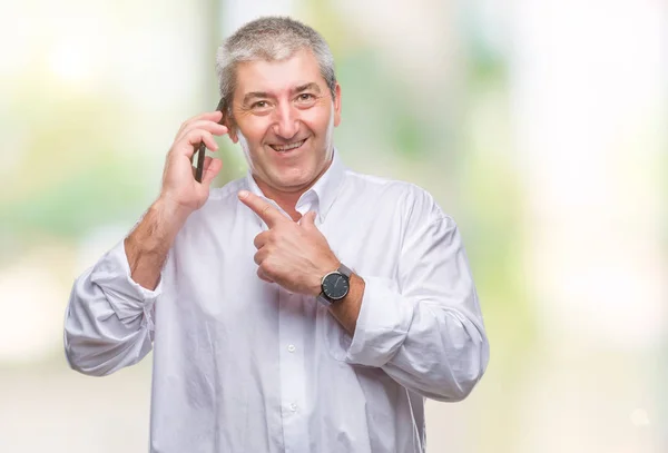 Handsome senior man talking on smartphone over isolated background very happy pointing with hand and finger