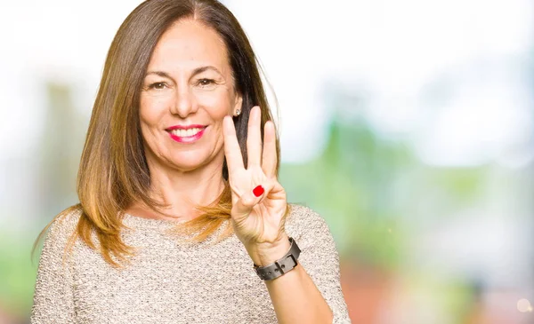 Beautiful middle age woman wearing fashion sweater showing and pointing up with fingers number three while smiling confident and happy.