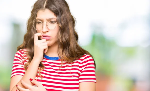 年轻的美丽的女人戴着眼镜 看上去压力很大 手放在嘴上咬指甲 焦虑问题 — 图库照片