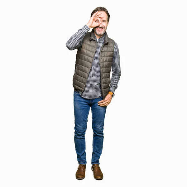 幸せそうな顔で指を通して見る目の手で のジェスチャーを行う冬のベストを着て中年ハンサムな男 — ストック写真