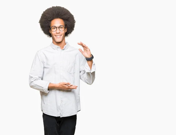 非洲青年美国人与非洲头发眼镜示意与手显示大和大尺寸的标志 措施符号 看着镜头微笑 测量概念 — 图库照片