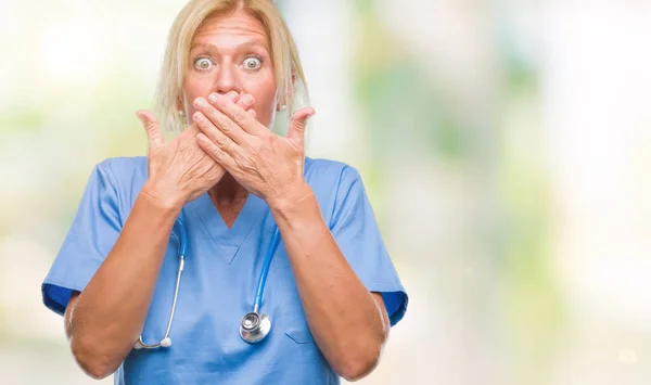中年金发碧眼的护士医生医生妇女在孤立的背景震惊覆盖嘴与手的错误 秘密概念 — 图库照片