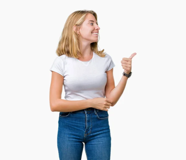 カジュアルな身に着けている美しい若い女性ことを笑って見て誇りに思って 分離の背景に白い シャツは親指側にジェスチャー — ストック写真