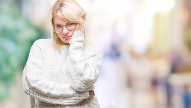 Kış kazak ve gözlük düşünme izole arka plan bakmaktan giyen genç güzel sarışın kadın yorgun ve sıkılmış çapraz silah depresyon sorunları ile.