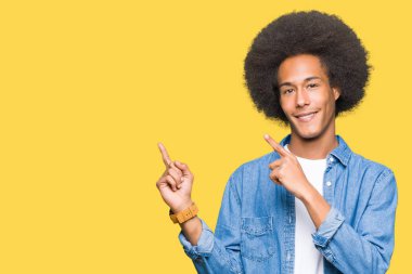 Gülümseyen ve iki elleri ve parmakları ile tarafına işaret kamera bakarak afro saçlı genç Afro-Amerikan adam.