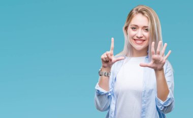 Genç Sarışın kadın gösterilen ve parmakları ile işaret izole arka plan yüzünden kendinden emin ve mutlu gülümseyerek süre yedi numara.