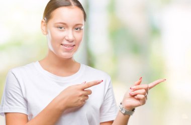 Genç güzel beyaz kadın gülümseyerek ve iki elleri ve parmakları ile tarafına işaret kamera bakarak izole arka plan üzerinde.