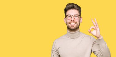 El ve parmak ile ok işareti yapıyor olumlu gülümseyen gözlüklü genç yakışıklı iş adamı. Başarılı ifade.