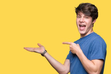 Üzerinden hayran ve el ile sunulması ve parmak ile işaret ederken kameraya gülümseyen izole arka plan mavi t-shirt giyen genç yakışıklı adam.