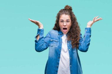 Üzerinde gözlük güzel genç esmer kıvırcık saçlı kız deli kutluyor arka plan izole ve çığlık kaldırdı ve açık gözleri heyecanlı silah ile başarı için hayrete düşürdü. Kazanan kavramı