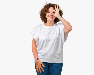 Gülümseyen, parmakları ile mutlu yüz üzerinden seyir göz el ile ok jest yapıyor izole arka plan üzerinde beyaz t-shirt giyen kadın güzel orta ager kıdemli.