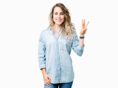 Gösterilen ve parmakları ile işaret izole arka plan üzerinde sarışın güzel genç kadın kendinden emin ve mutlu gülümseyerek iken üçüncü.