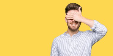 Gülümseyen ve gülen genç yakışıklı adam şaşırmak için gözlerini kapatıyor. Kör kavram.