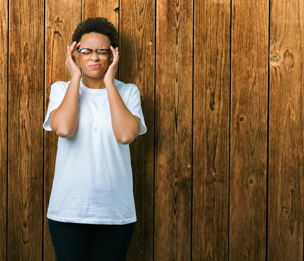 Güzel genç Afro-Amerikan kadın gözlük ile izole arka plan üzerinde baş ağrısı için kafasına çünkü el stres. Migren muzdarip.