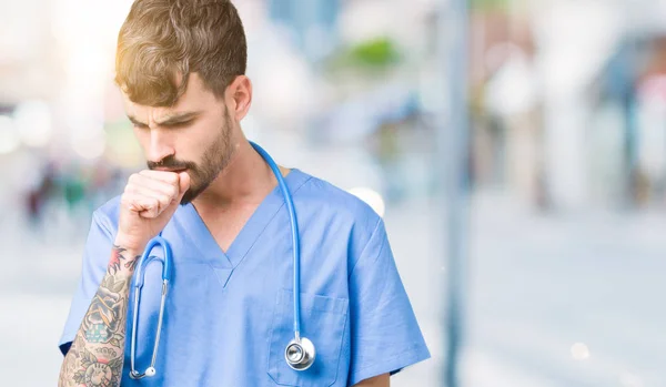 Young handsome nurse man wearing surgeon uniform over isolated background feeling unwell and coughing as symptom for cold or bronchitis. Healthcare concept.