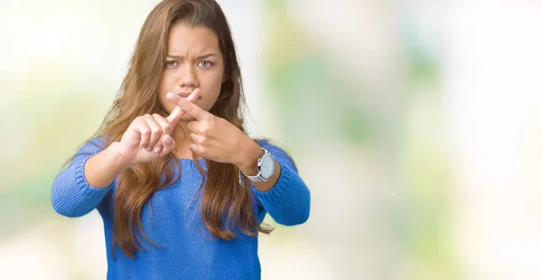 年轻美丽的黑发女人穿着蓝色毛衣在孤立的背景拒绝表达交叉手指做消极的标志 — 图库照片
