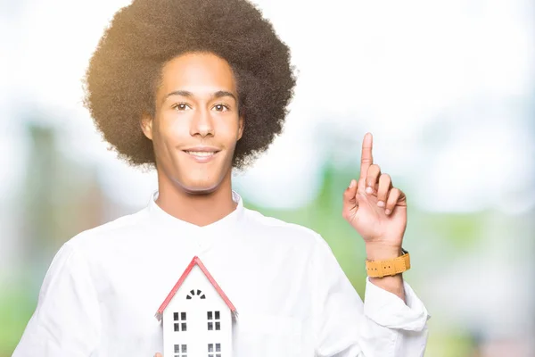 幸せそうな顔 ナンバーワンのアイデアや質問ポインティング指で家を保持してアフロの髪の若いアフリカ系アメリカ人を驚かせた — ストック写真