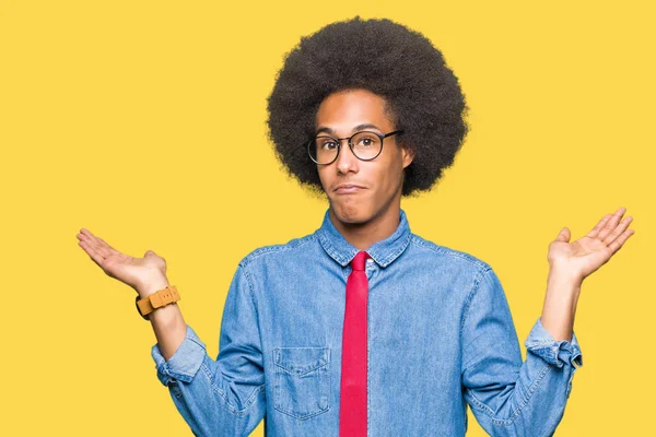 眼鏡と腕と手を上げて赤いネクタイの無知と混乱式アフロの髪の若いアフリカ系アメリカ人ビジネスマン疑いのコンセプト — ストック写真