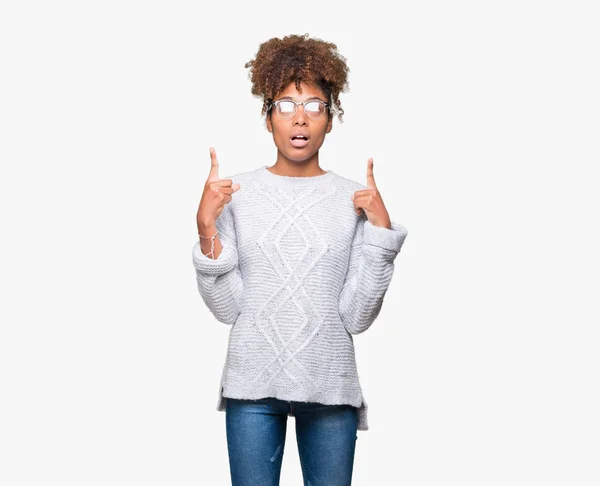 美丽的年轻非洲裔美国妇女穿着冬季毛衣在孤立的背景惊讶和惊讶地抬头 用手指指指点点 举起双臂 — 图库照片