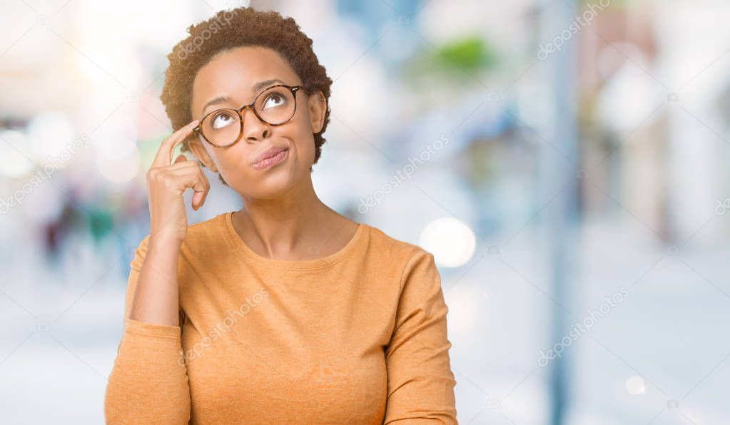 Young beautiful african american woman wearing glasses over isolated background with hand on chin thinking about question, pensive expression. Smiling with thoughtful face. Doubt concept.